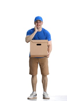 A male deliveryman, on a white background, full-length, with a box, tells a secret.