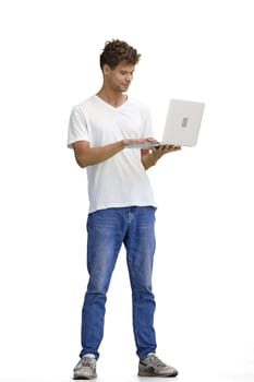 A man in a white T-shirt, on a white background, in full height, uses a laptop.