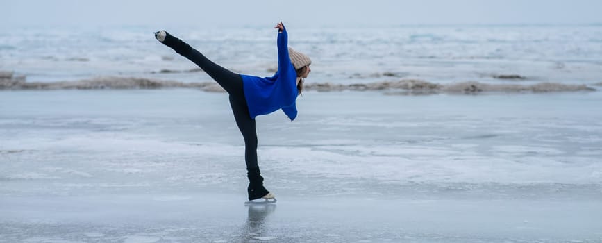 Caucasian woman in a blue sweater is skating on a frozen lake. Figure skater performs a swallow