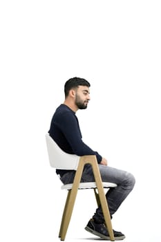 A man, on a white background, sitting on a chair.