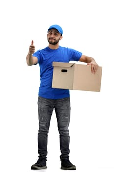 The deliveryman, in full height, on a white background, with a box, shows a thumbs up.