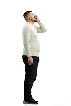 A man, full-length, on a white background, yawns.