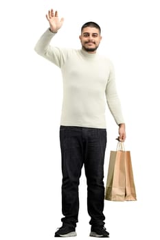 A man, full-length, on a white background, with bags, waving his hand.