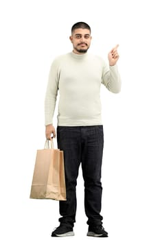 A man, full-length, on a white background, with bags, points up.