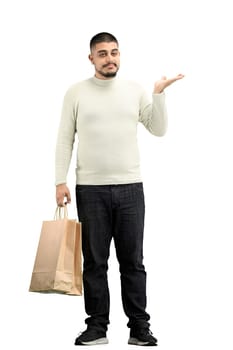 A man, full-length, on a white background, with bags, points to the side.