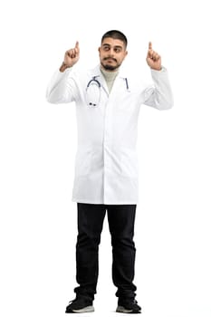 The doctor, in full height, on a white background, points up.
