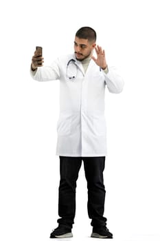 The doctor, in full height, on a white background, talking on the phone.