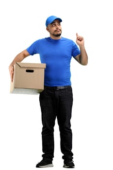 The deliveryman, in full height, on a white background, with a box, points up.