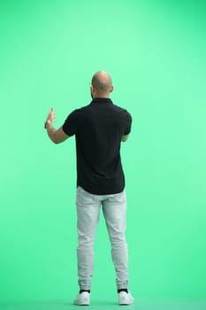 A man, on a green background, in full height, spreads his arms.