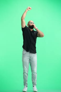 A man, on a green background, in full height, rejoices.