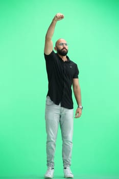 A man, on a green background, in full height, raised his hand.