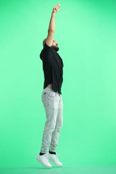 A man, on a green background, in full height, jumps.