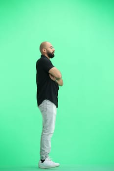 A man, on a green background, in full height, crossed his arms.