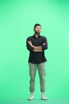 A man, on a green background, in full height, crossed his arms.