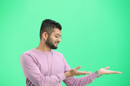 A man, on a green background, in close-up, points to the side.