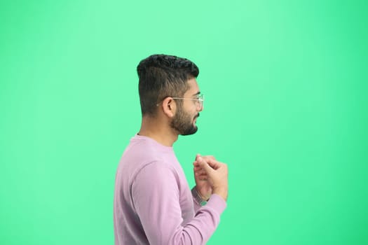 A man, on a green background, in close-up, points to the side.