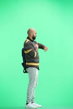 A man, on a green background, full-length, with a backpack.