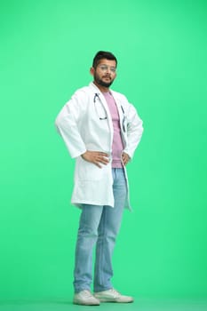 Male doctor, on a green background, full-length, hands on hips.