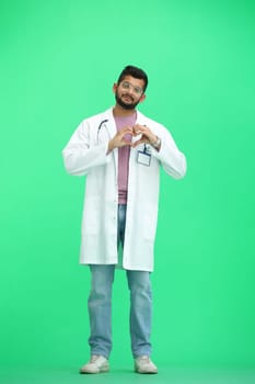 A male doctor, on a green background, in full height, shows a heart.