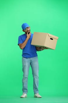 A male deliveryman, on a green background, in full height, thinks.