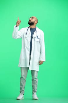 The male doctor, on a green background, in full height, points up.