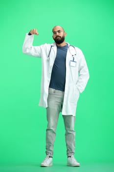 A male doctor, on a green background, in full height, shows strength.