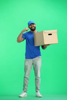 A male deliveryman, on a green background, in full height, with a box, shows a call sign.