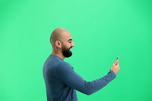 Man, on a green background, close-up, with a phone.