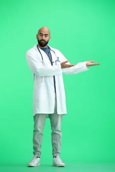 The male doctor, on a green background, in full height, points to the side.