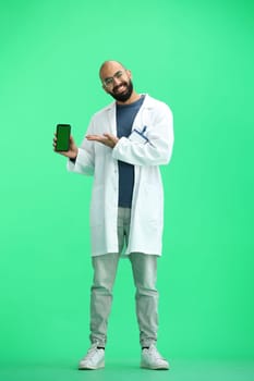 Male doctor, on a green background, full-length, with a phone.