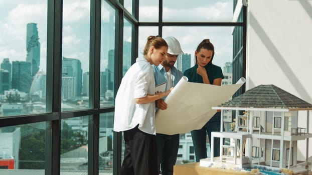 Professional architect engineer team talking, sharing, brainstorming about design while manager hold at project plan. Young architect holding plan while manager listen and point at plan. Tracery