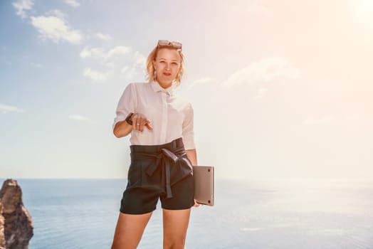 Digital nomad, Business woman working on laptop by the sea. Pretty lady typing on computer by the sea at sunset, makes a business transaction online from a distance. Freelance, remote work on vacation