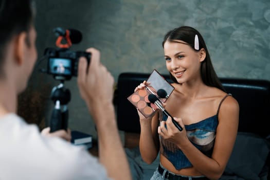 Man filming video on young woman making beauty and cosmetic tutorial video content for social media. Beauty blogger smiles to camera while showing how to beauty care to audience or follower. Unveiling