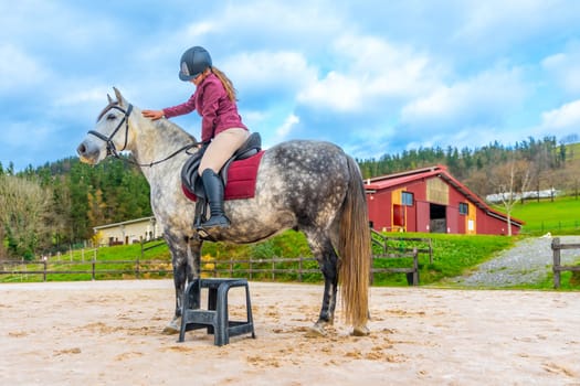 Girl with protective gear riding a horse in an equestrian center