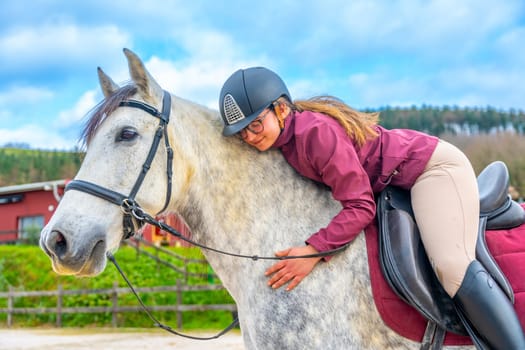 Woman embracing a horse while riding it in an equestrian center