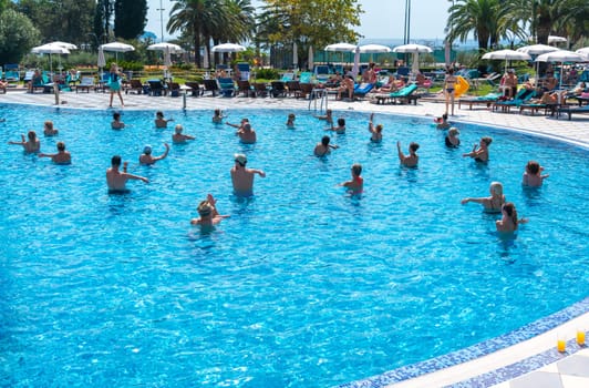BUDVA, MONTENEGRO - SEPTEMBER 08, 2023: Vacationers partake in a lively aqua aerobics session in the hotel's outdoor pool, blending the excitement of sport with the pleasure of group activities. Concept of leisure and health