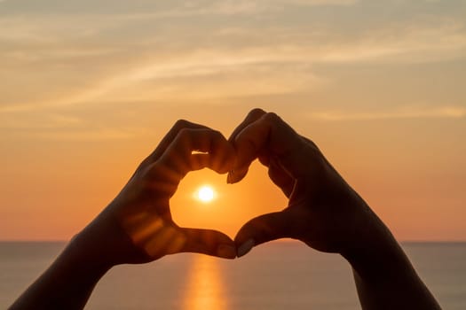 Hands heart sea sanset. Hands forming a heart shape made against the sun sky of a sunrise or sunset on a beach.