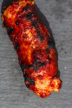 Close up of grilled sausage on small black cutting board isolated. Barbecue, grill and food concept.