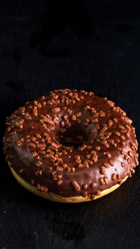 Chocolate glazed donut with chocolate chips isolated. Close up of delicious donut.