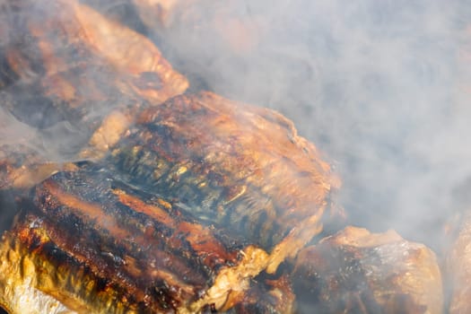 Grilled mackerel fish with smoke on a charcoal barbecue grill.