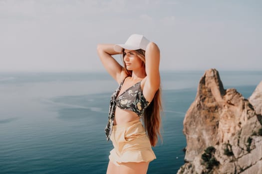 Woman travel sea. Happy tourist taking picture outdoors for memories. Woman traveler looks at the edge of the cliff on the sea bay of mountains, sharing travel adventure journey.