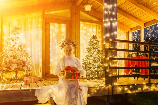 A woman in a white dress holding a gift box.