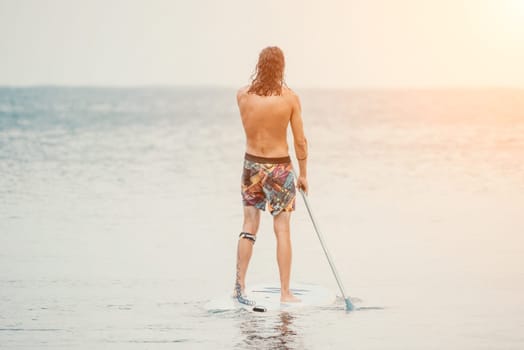 Sea woman and man on sup. Silhouette of happy young woman and man, surfing on SUP board, confident paddling through water surface. Idyllic sunset. Active lifestyle at sea or river