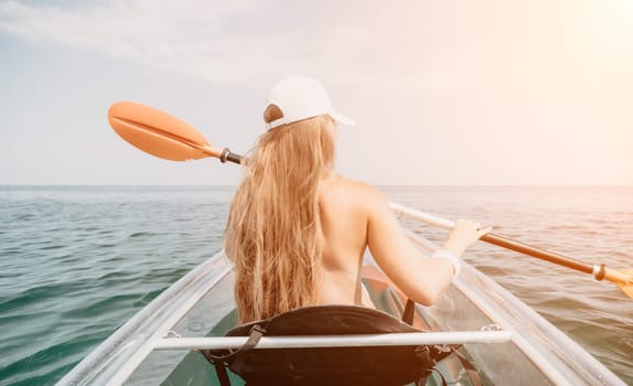 Woman in kayak back view. Happy young woman with long hair floating in transparent kayak on the crystal clear sea. Summer holiday vacation and cheerful female people having fun on the boat.