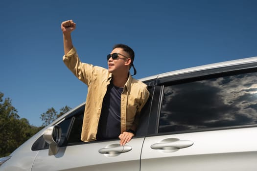 Overjoy young man on the road trip travel vacation leaning out from car window. Travel and transportation concept.