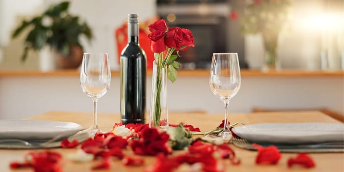 Wine, flowers and romance on valentines day for celebration of love, anniversary or honeymoon in still life. Glass, dinner and elegant date in dining room of home for event, milestone or occasion.