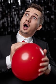 amazed man in black jacket with red air balloon at birthday party