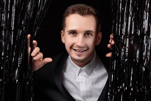 Happy handsome man in black jacket smiling on glitter background.