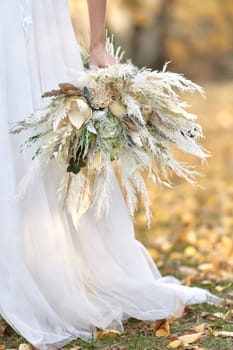 hands of the bride holding beautiful autumn bouquet outdoor