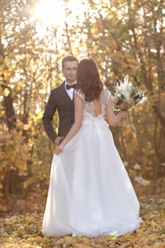 beautiful bride in white wedding dress and groom standing outdoor on natural background in sunny day